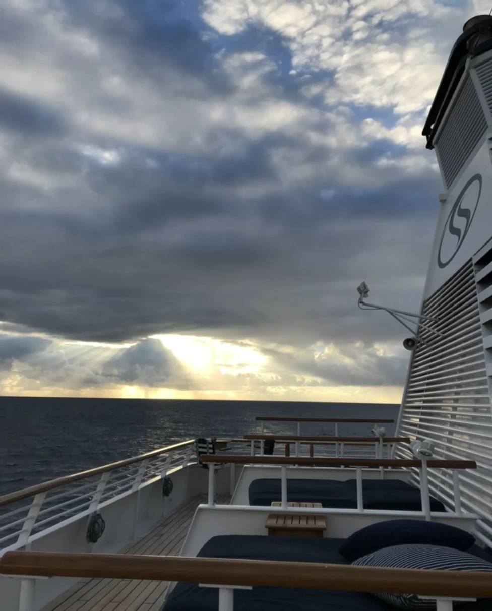 Lounge chairs on a yacht deck with a sea view on a cloudy day.