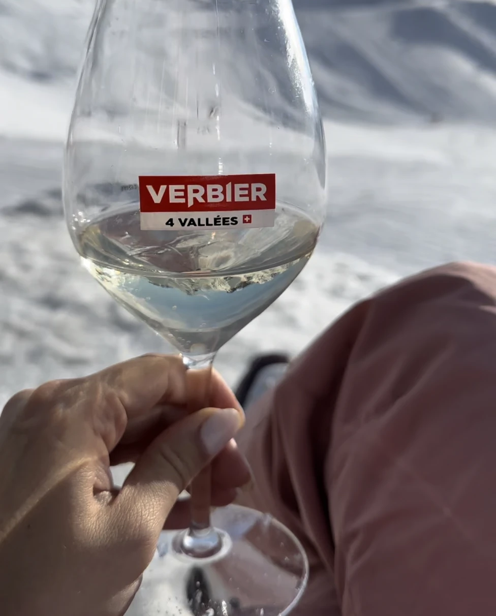 a wine glass in hand at the top of a ski mountain