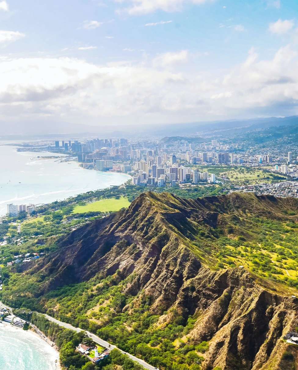 aerial view of mountains next to body of water and city
