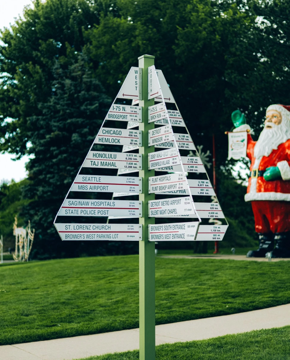 A street sign with santa clause in the background.