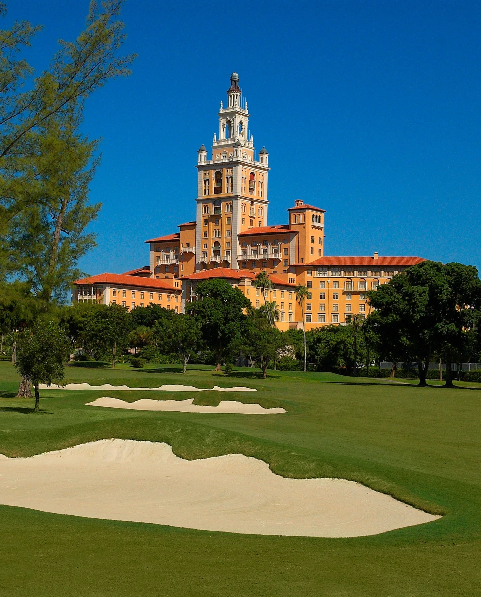 A large orange building behind a golf course during the daytime