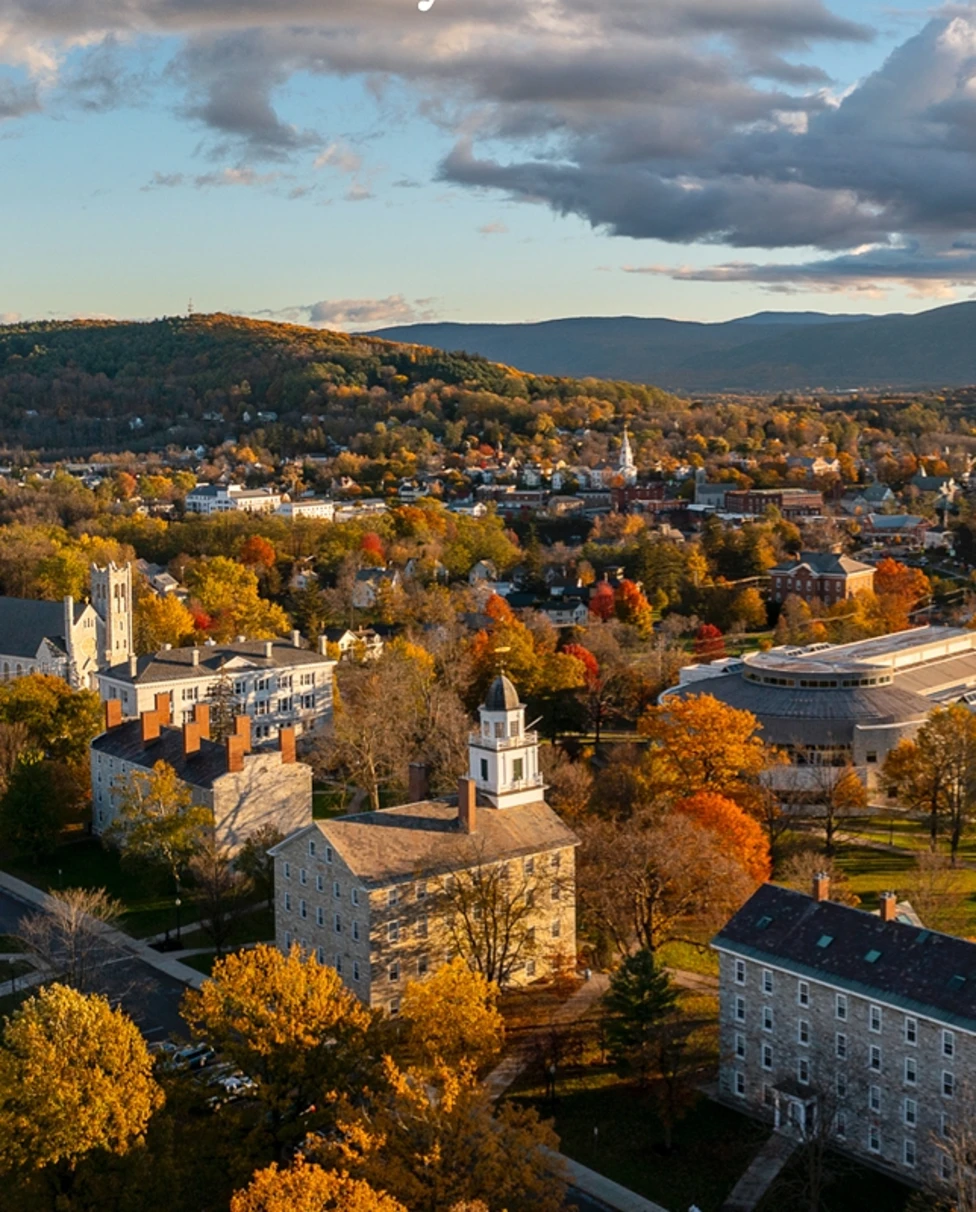 An aerial view of a autumnal town with mountains in the background.