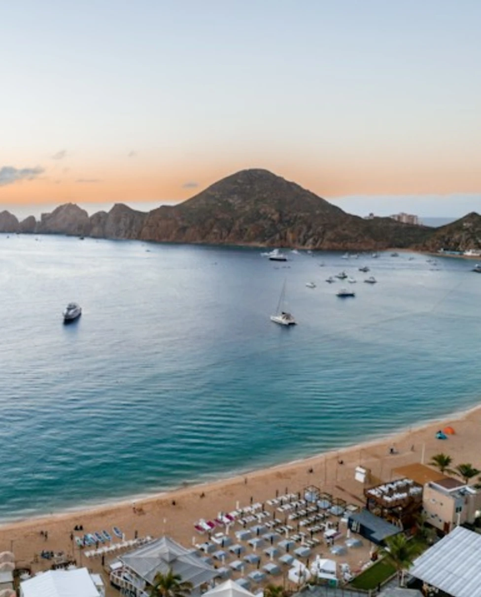 a beach with boats and a hill in the background