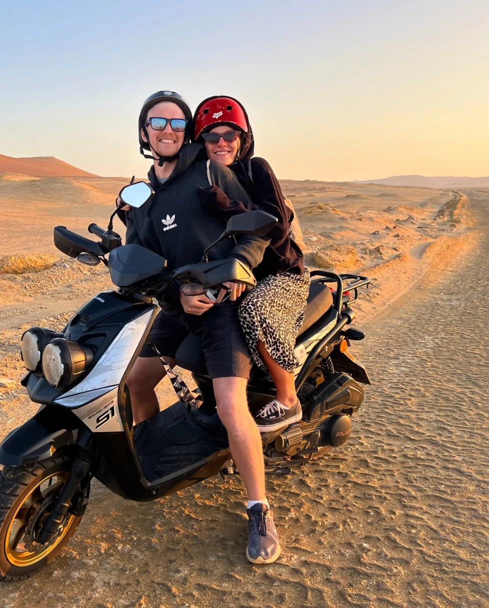A man and woman on a motorcycle in a dessert.