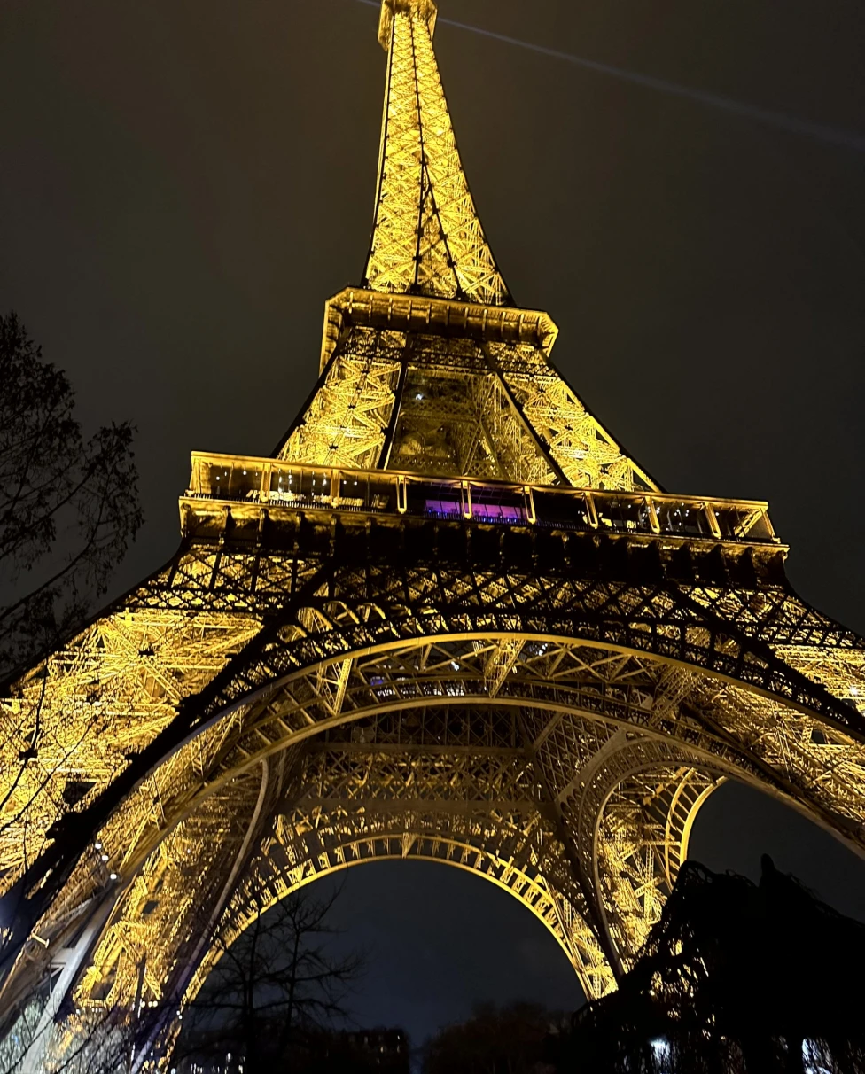 A view of the iconic Eiffel Tower illuminated at night from underneath.