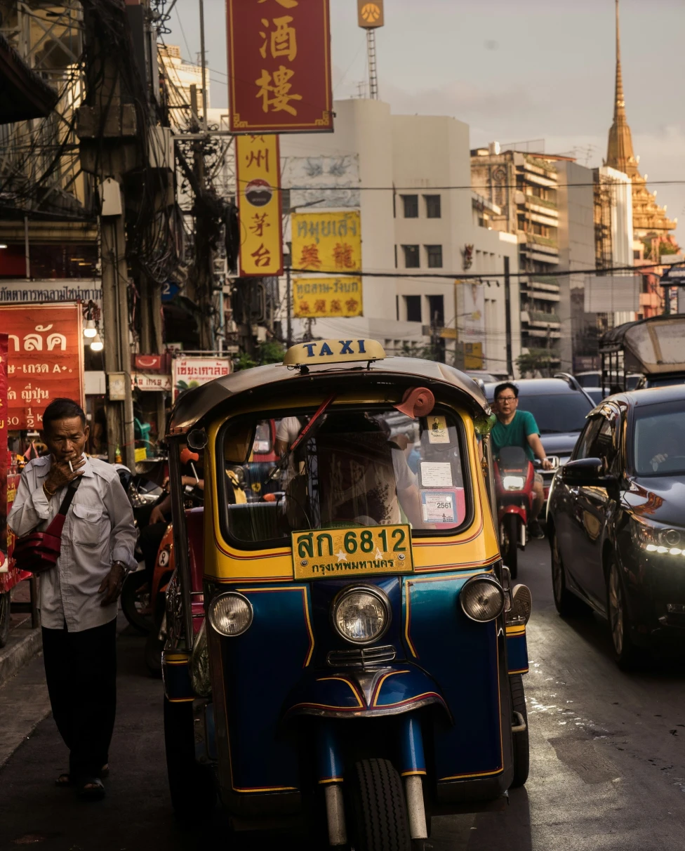 Taxi in traffic on a bustling city street at dusk.