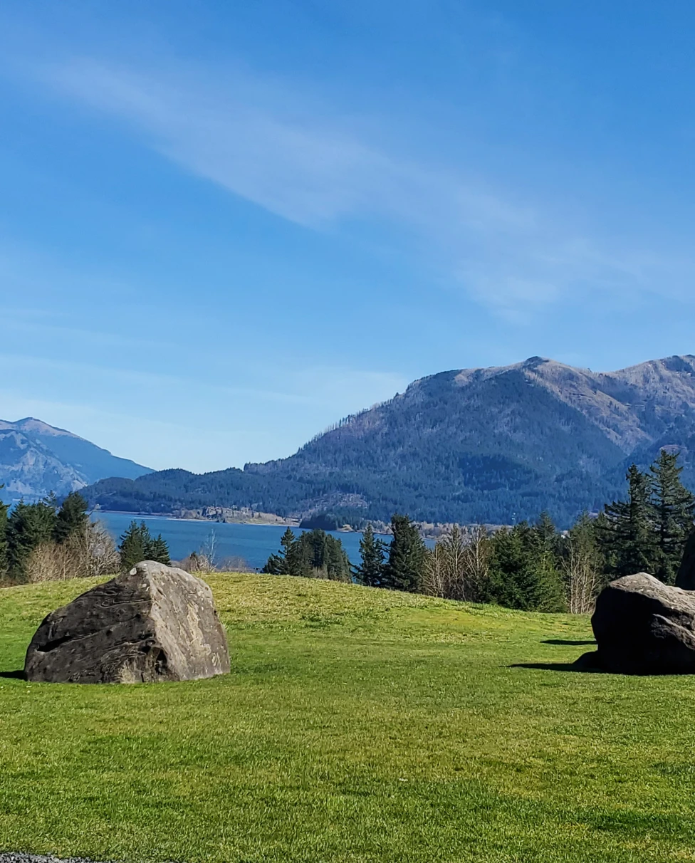A photo of boulders, a lake and the Columbia River Gorge in the background.