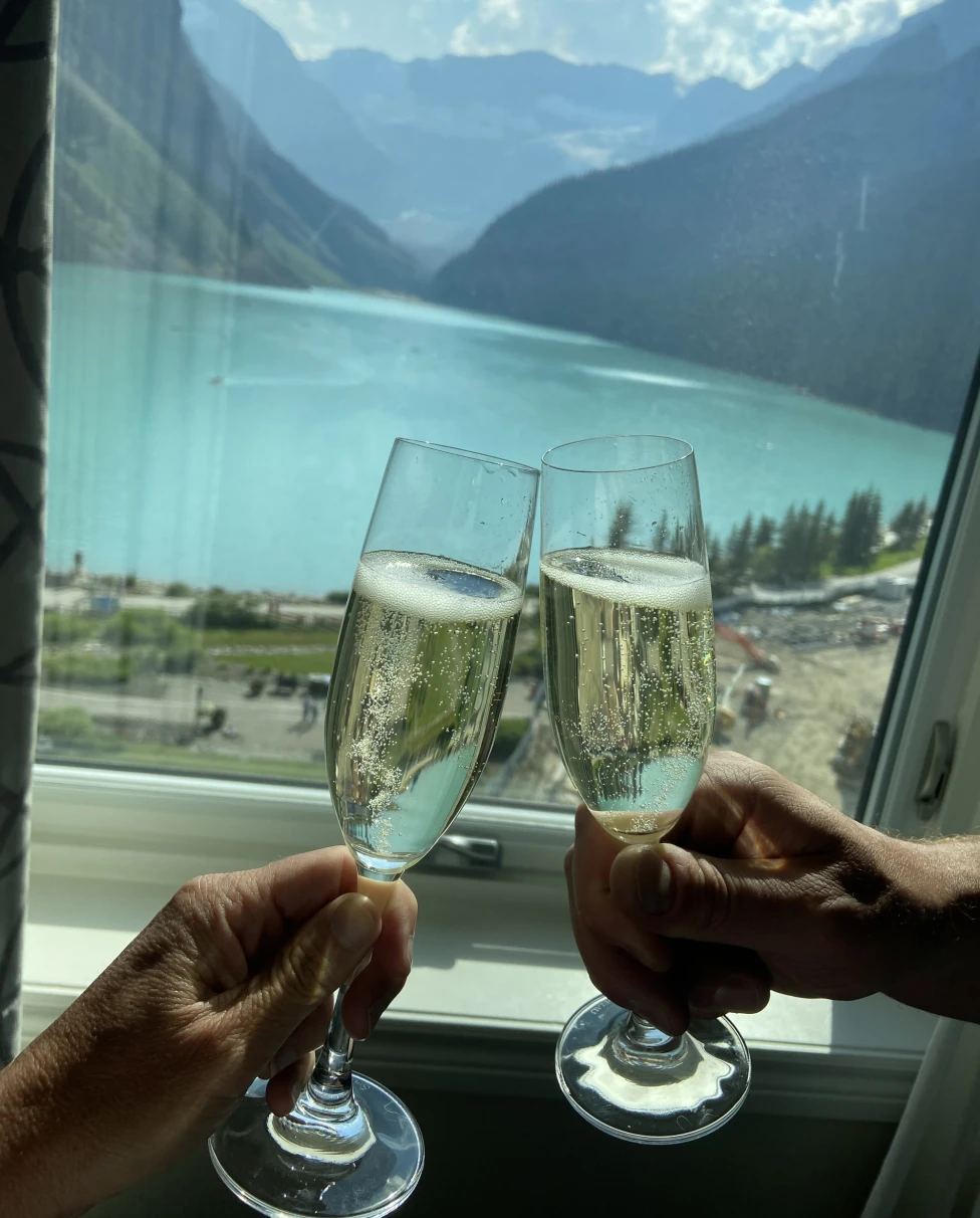 Two wine glasses being tossed in front of a lake.