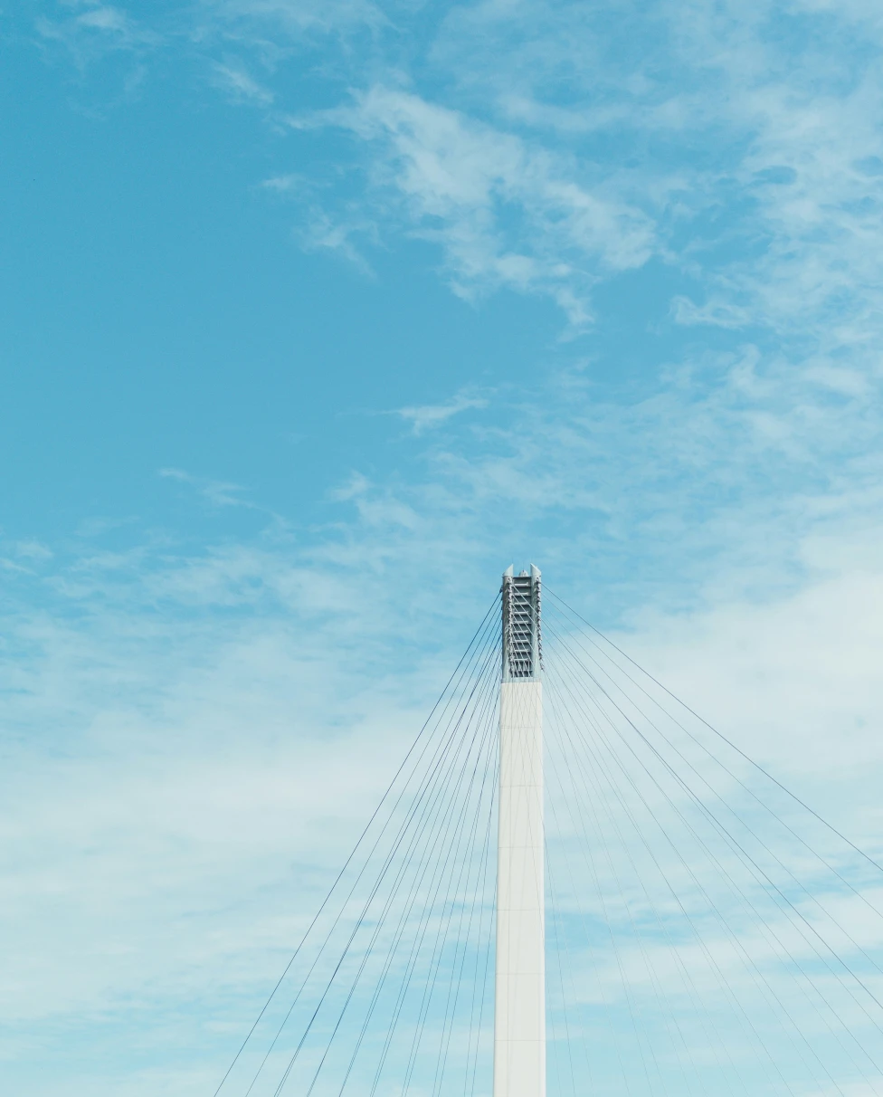 The top of a white bridge spire against a blue sky.