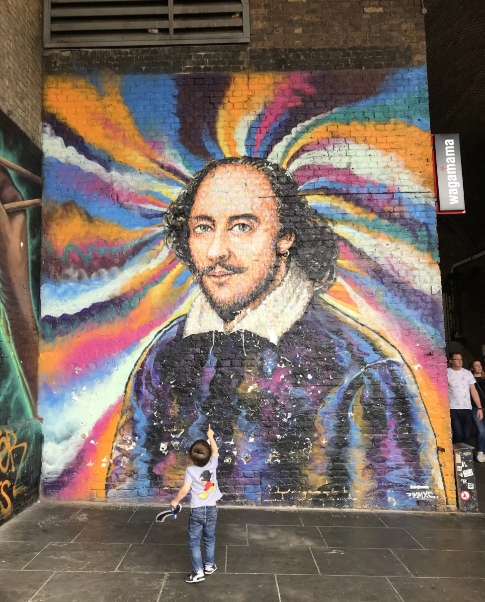 Kid looking and pointing at colorful wall art of a man.