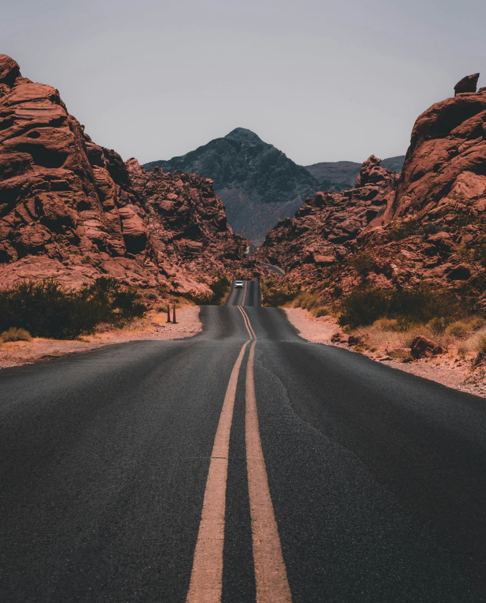 A road winds between rocky mountains that stretch to the horizon on a clear day.