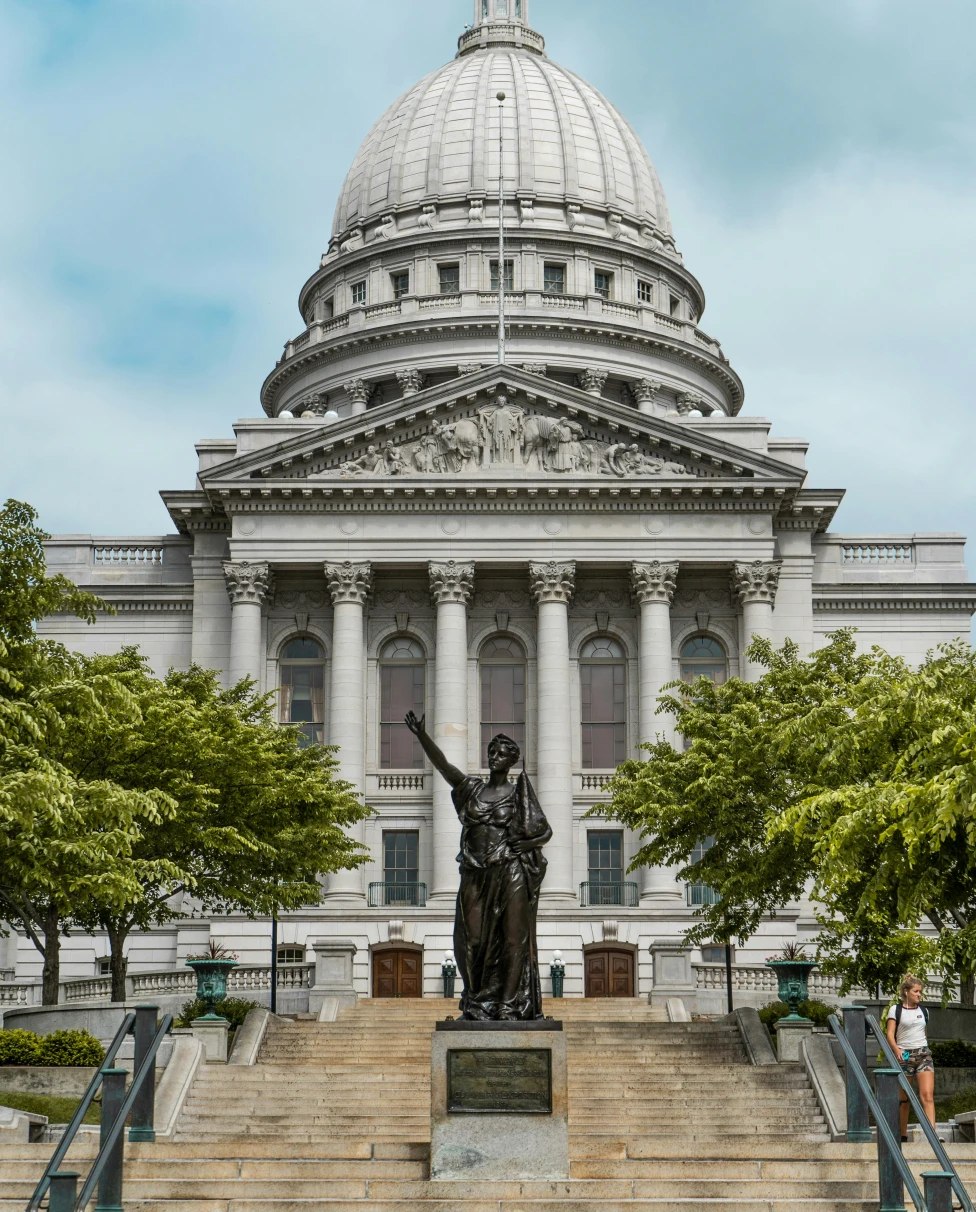 A state building with an arched windows, a statue and steps leading to the entrance.