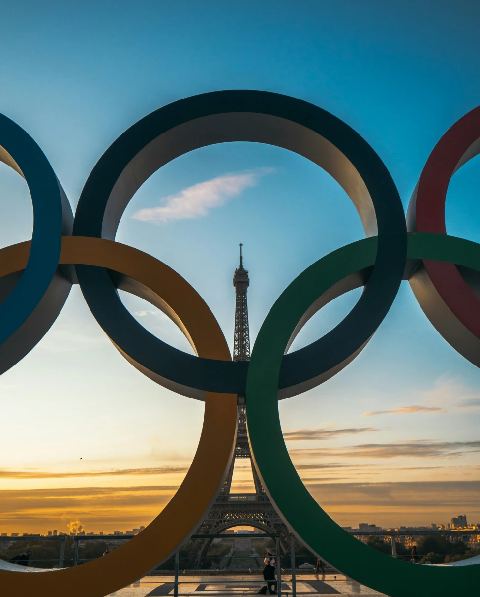 A low angled shot of the Olympics rings in front of the Eiffel Tower.