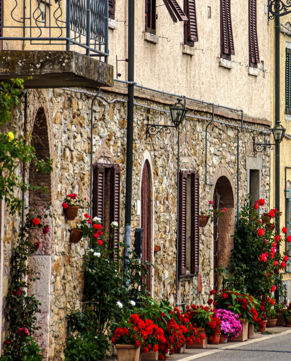 An Italian building with red and pink flowers.