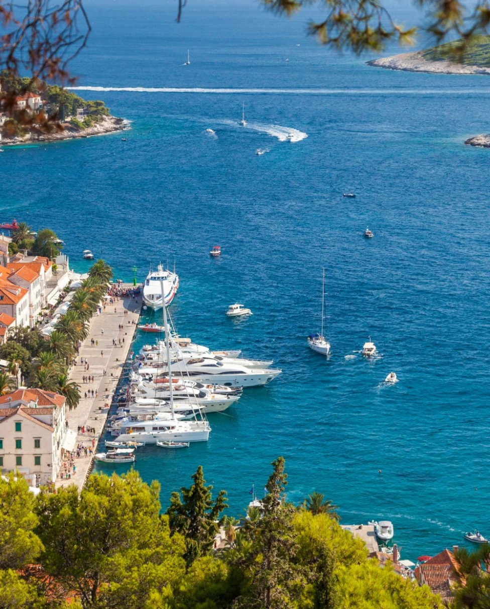 An ocean view from high up with boats and yachts in the distant waters.