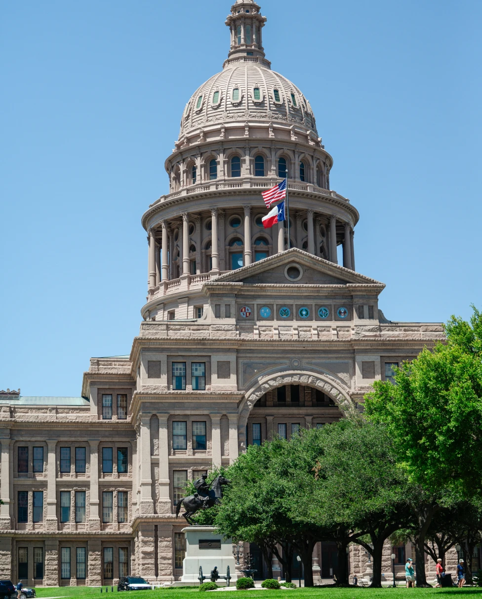 Capitol building with grass and flags with blue sky in Austin, Texas