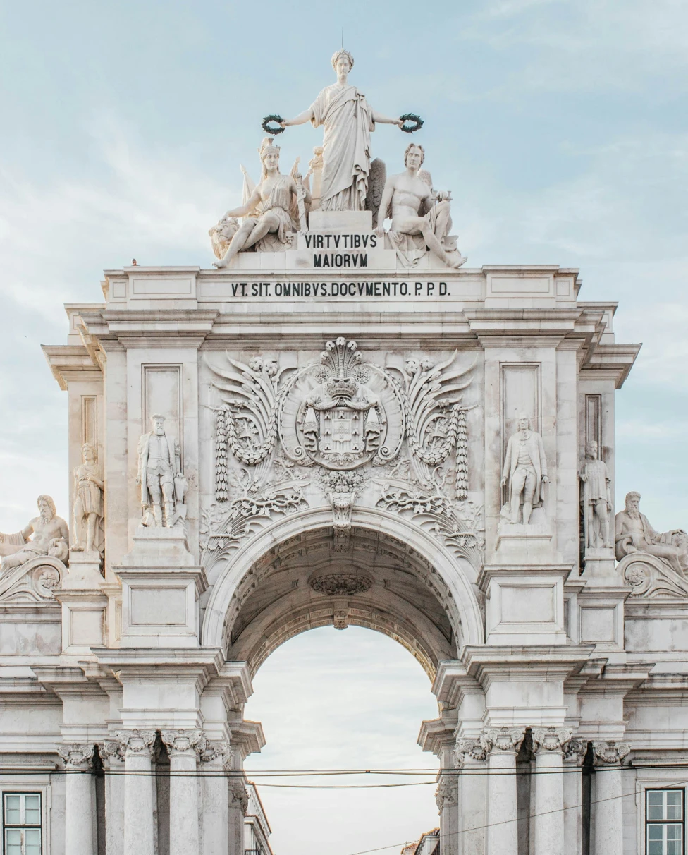 An ornate stone archway with Latin inscriptions and sculptures under a clear sky.