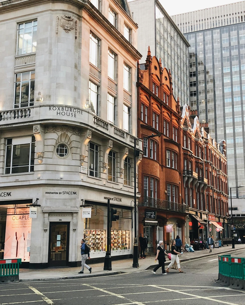 The image shows a city street with pedestrians and a mix of modern and traditional architecture.