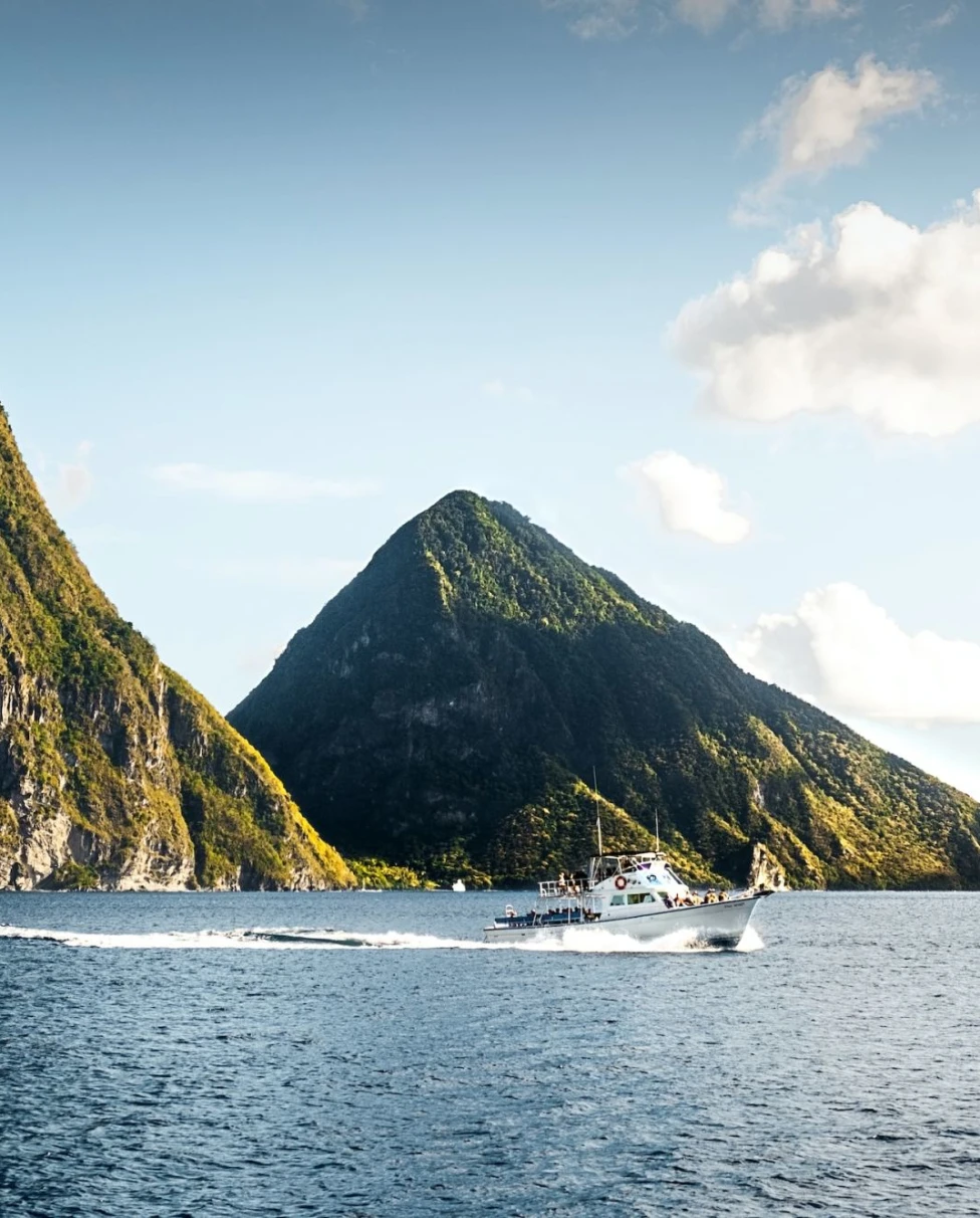 the twin volcanic peaks of Piton's Peak across the bay with a tour boat taking travelers around the island (photo by Daniel Öberg)