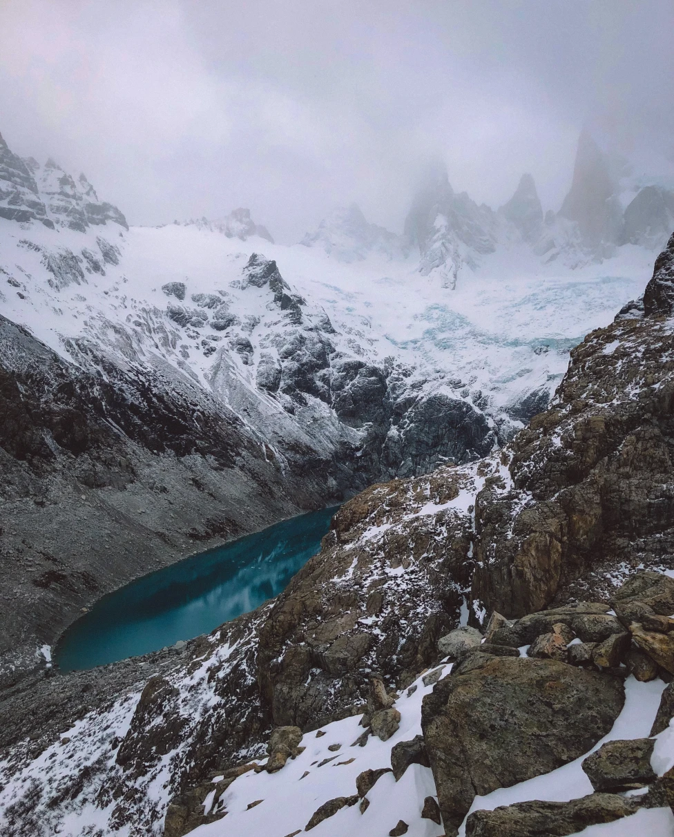 Snow-covered mountains and blue water on a cloudy day