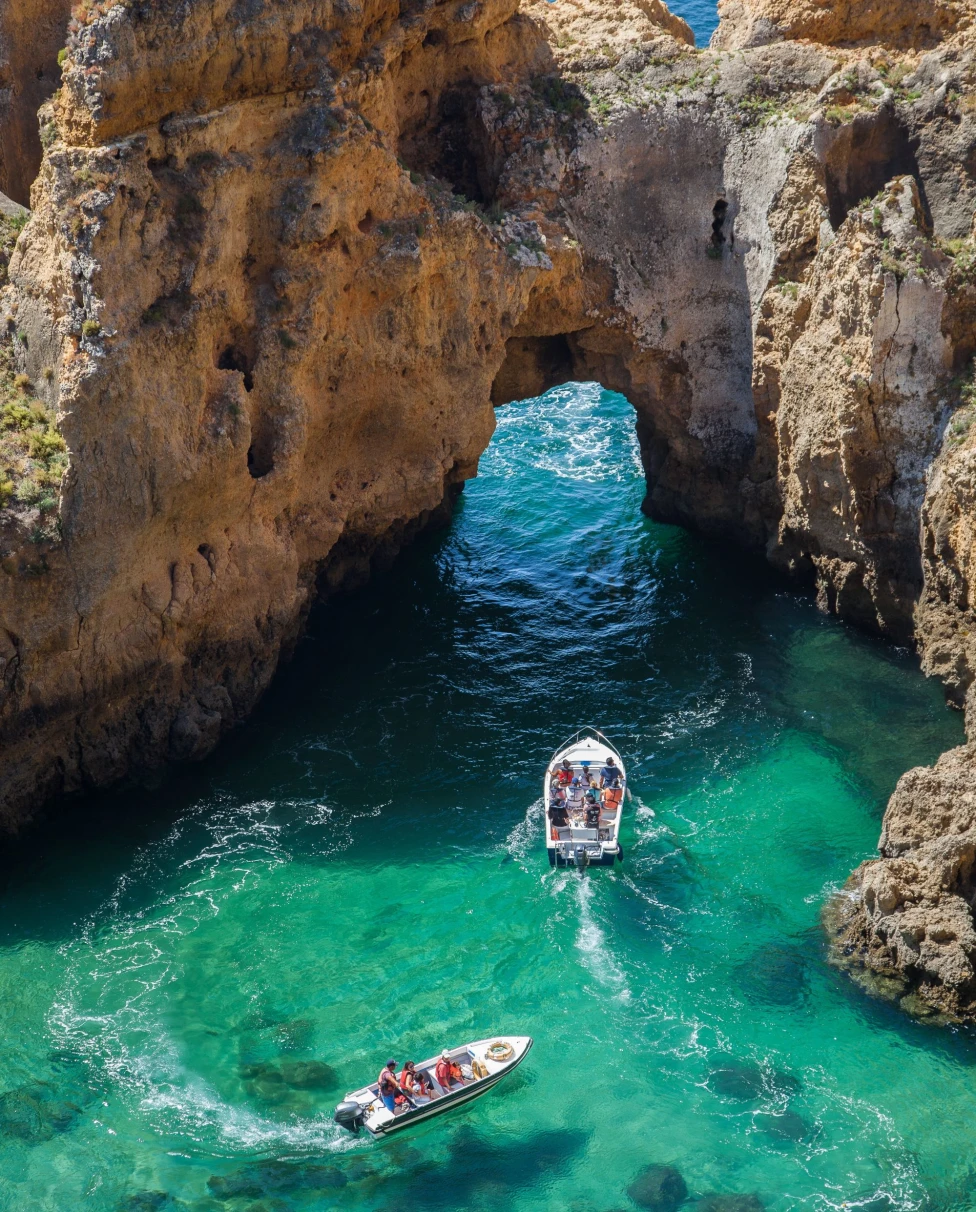 rock structure of an arch in the ocean with two boats