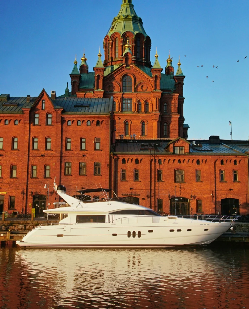 A white yacht on the waterfront of Uspenski Cathedral on a sunny day.