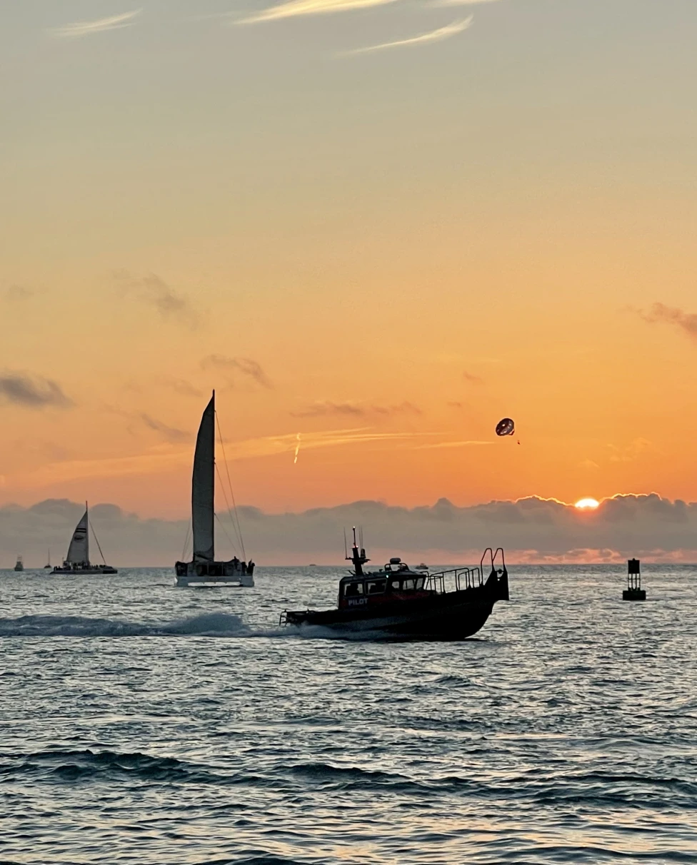 A sunset over the water with boats in the distance