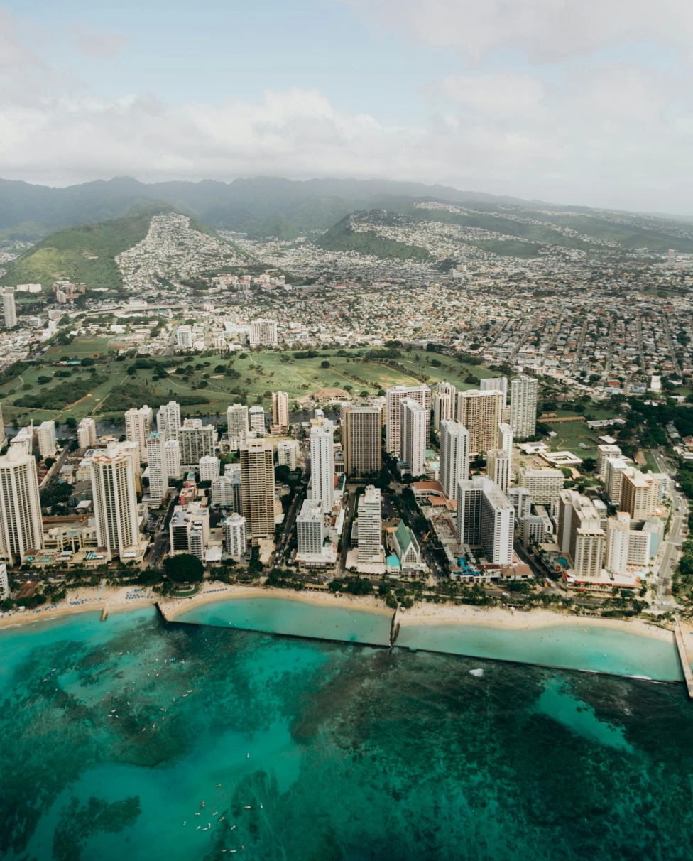 An aerial view of Oahu's city skyline with skyscrapers on the coast with turquoise water
