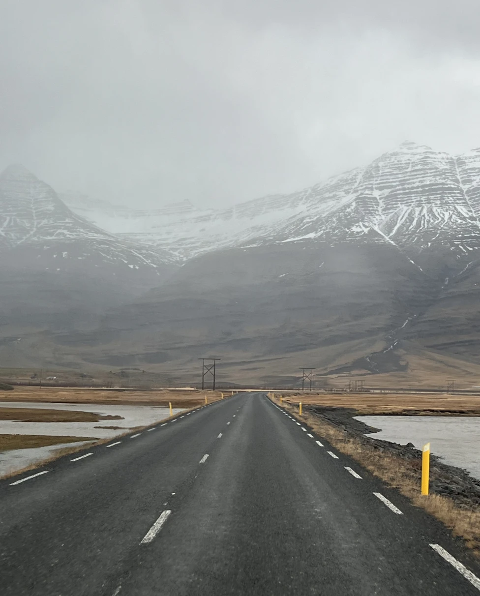 A serene mountainous landscape enveloped in mist, as seen from an empty road