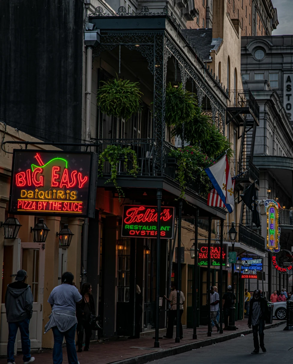 An image of downtown NOLA at dusk with 'Big Easy' establishment neon signs lit up.