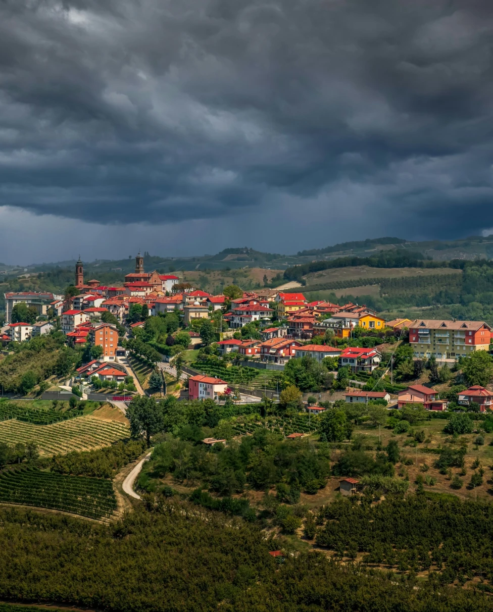 A picturesque hilltop village under a dramatic cloudy sky.