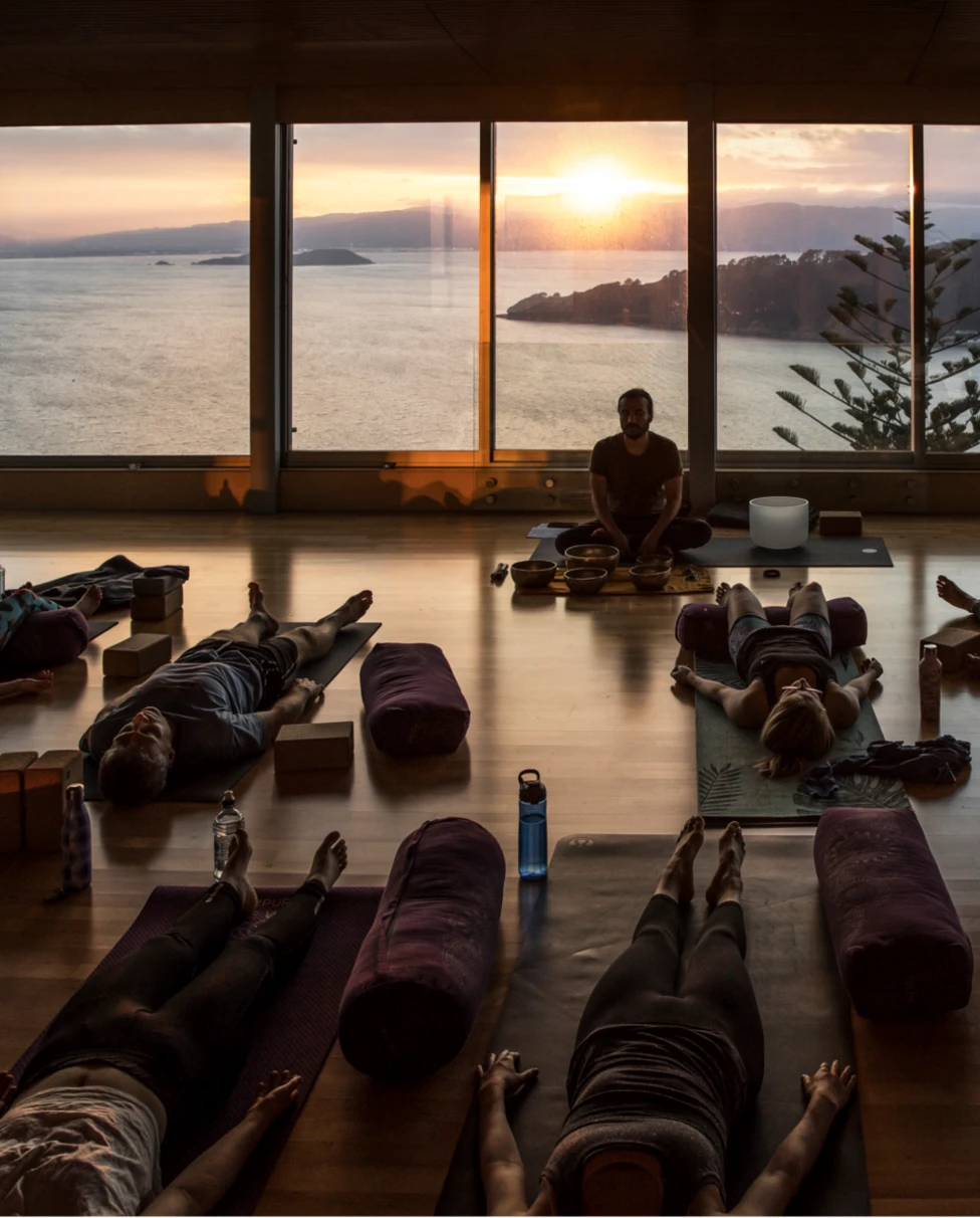 The image depicts a waterfall cascading down a vertical cliff surrounded by lush foliage under a clear blue sky.