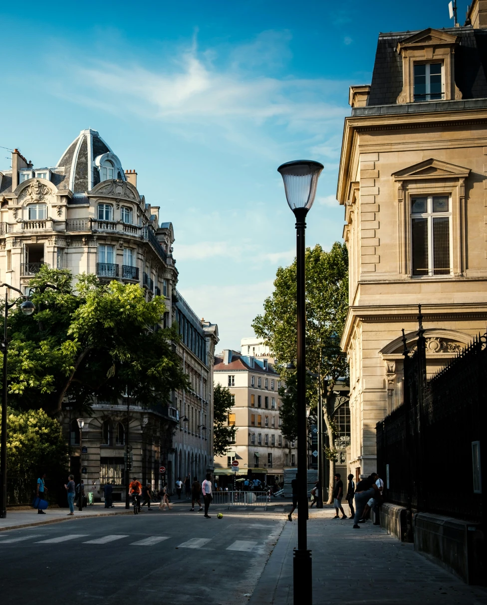 A street in the Paris 3rd arrondissement, with a large Hausmannian building next to a green park.