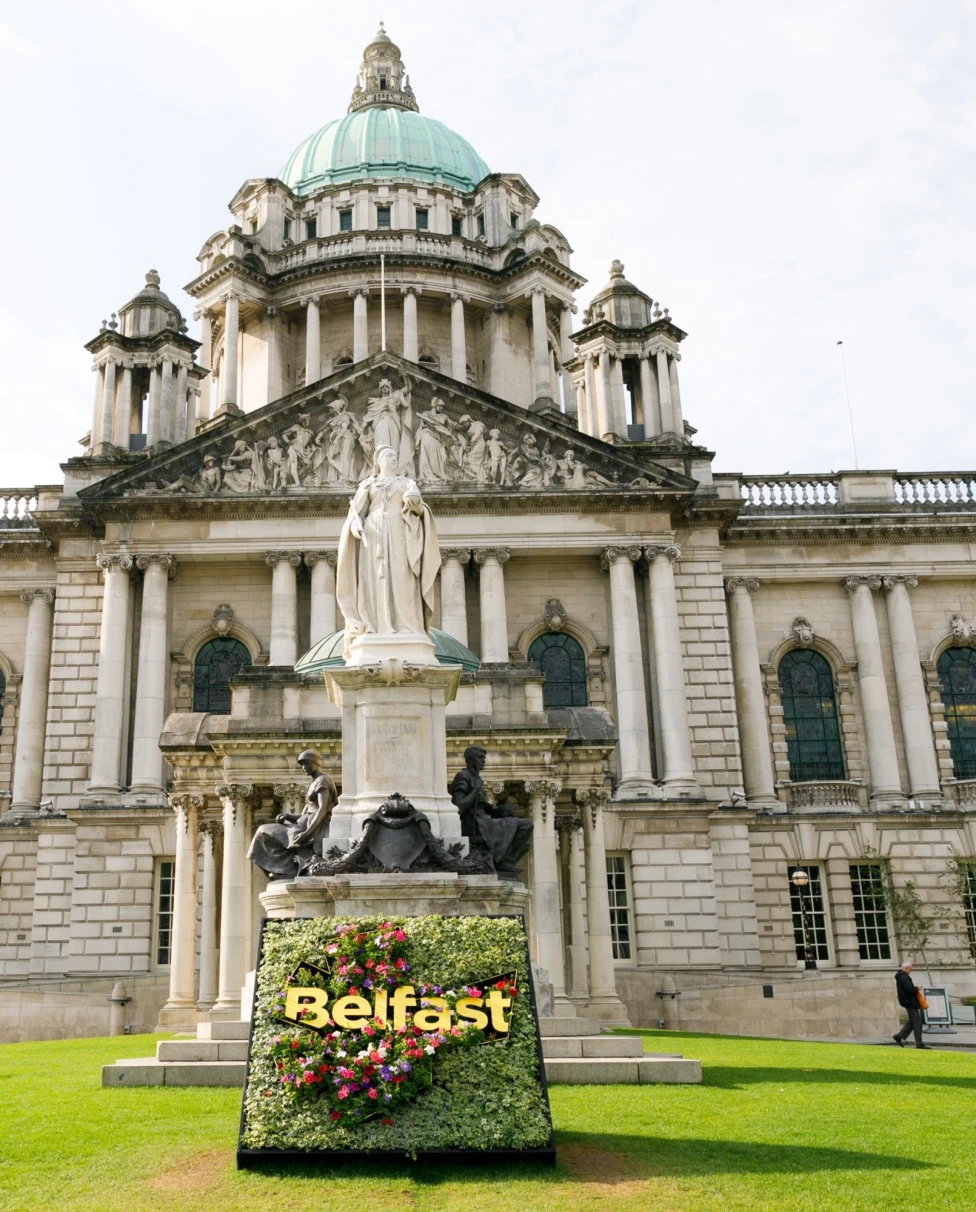 A picture of a white concrete building with green grass lawn taken during the daytime.