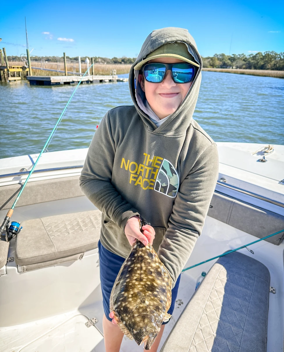 A picture of a person on a boat holding a fish during the daytime.