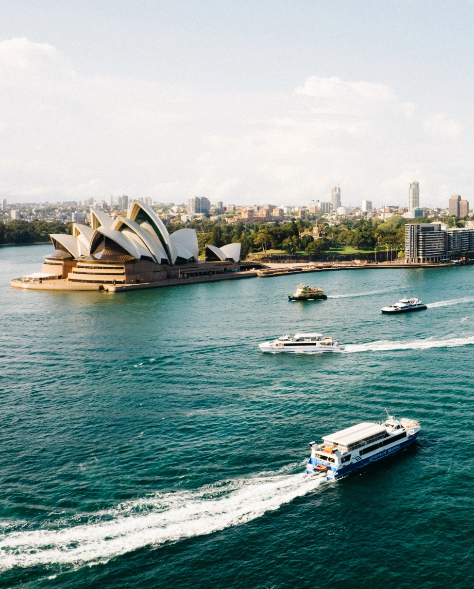 A skyline of Sydney with sea, boats and buildings.