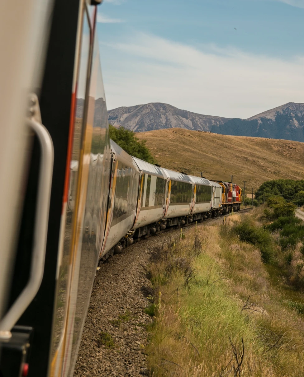 train on track with mountains in the background during daytime