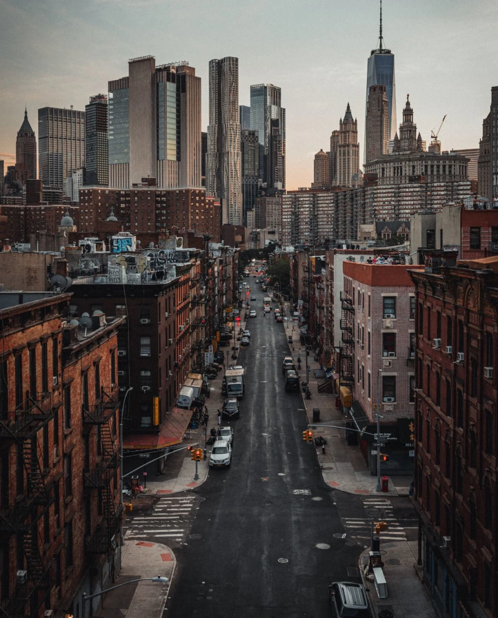 cars parked on a street overlooking New York City's skyline