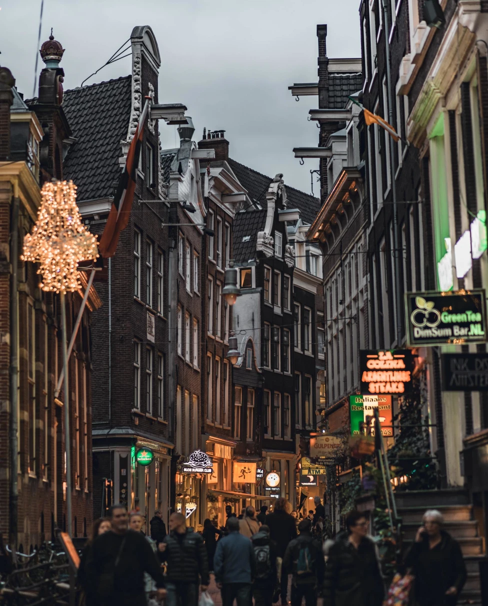 narrow busy streets of an old city in the afternoon with lit up shop windows
