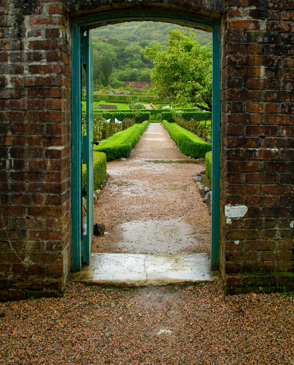 A door in a brick wall leading to a manicured garden, which you might see on an Ireland honeymoon.