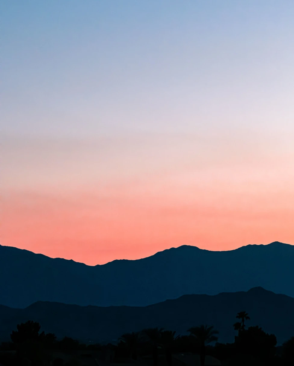 silhouette of a mountain range under a blue to pink sunset
