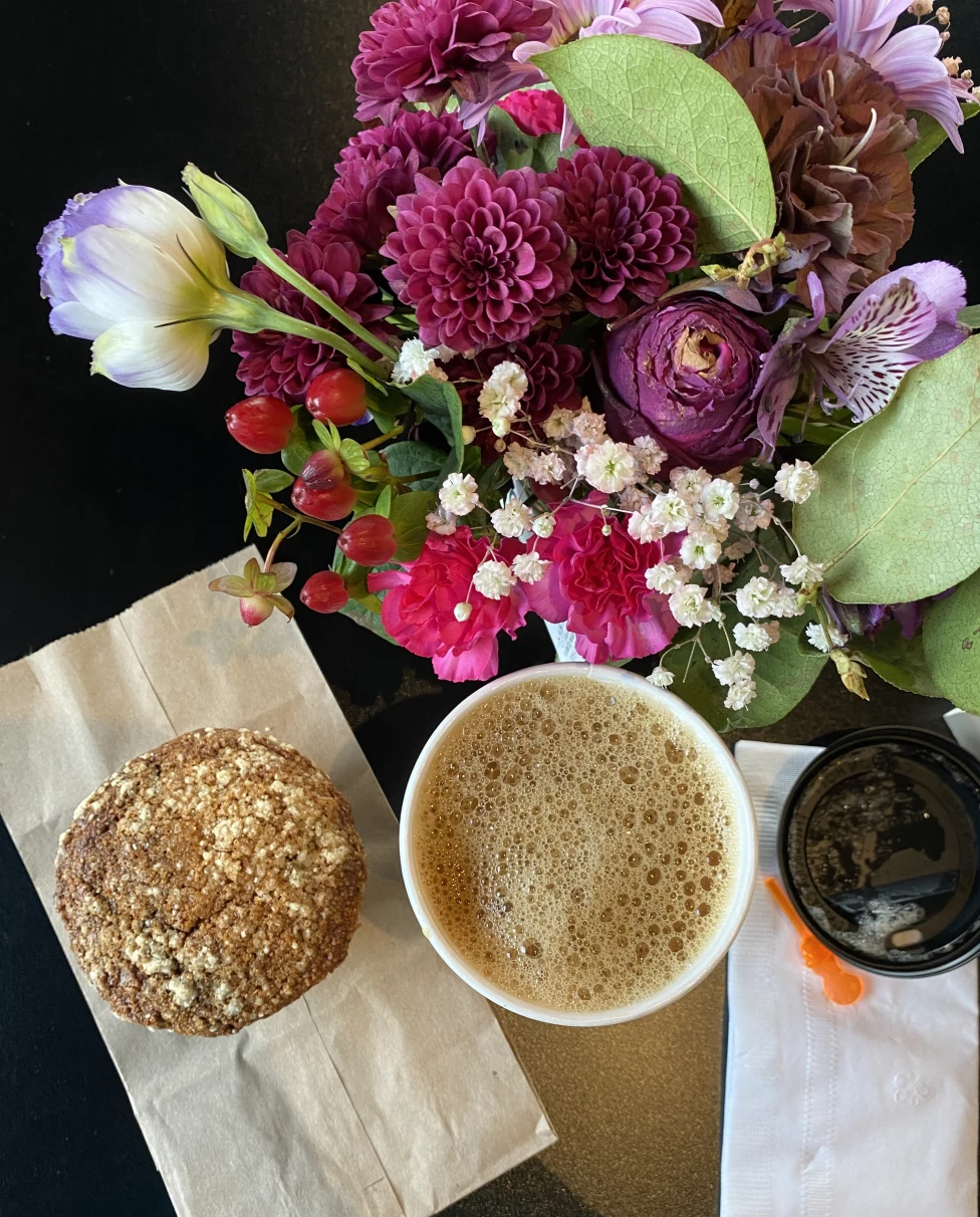 An iced coffee in a plastic to-go cup on a wooden counter.