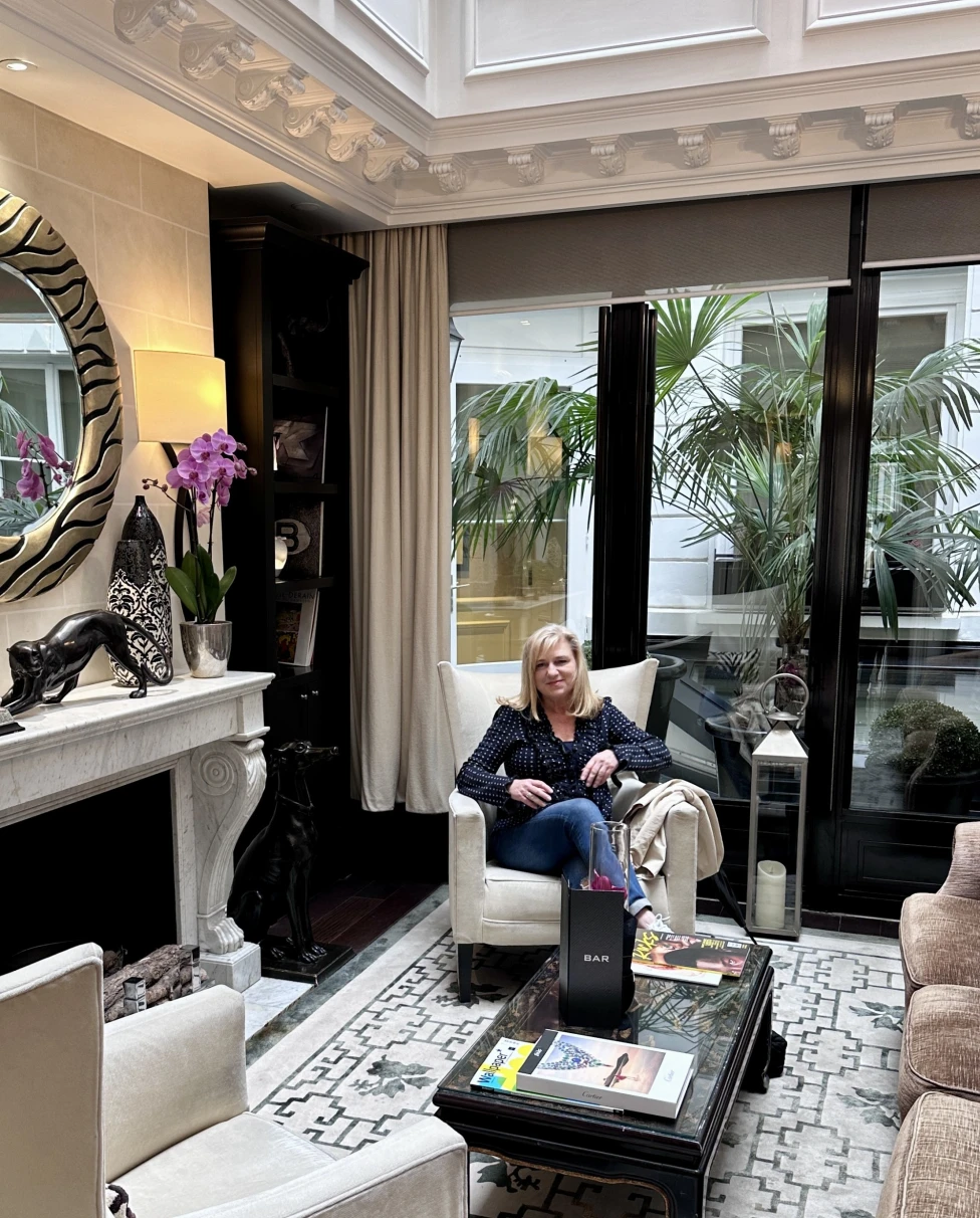 Travel advisor posing in a sitting chair of a luxurious hotel lobby.