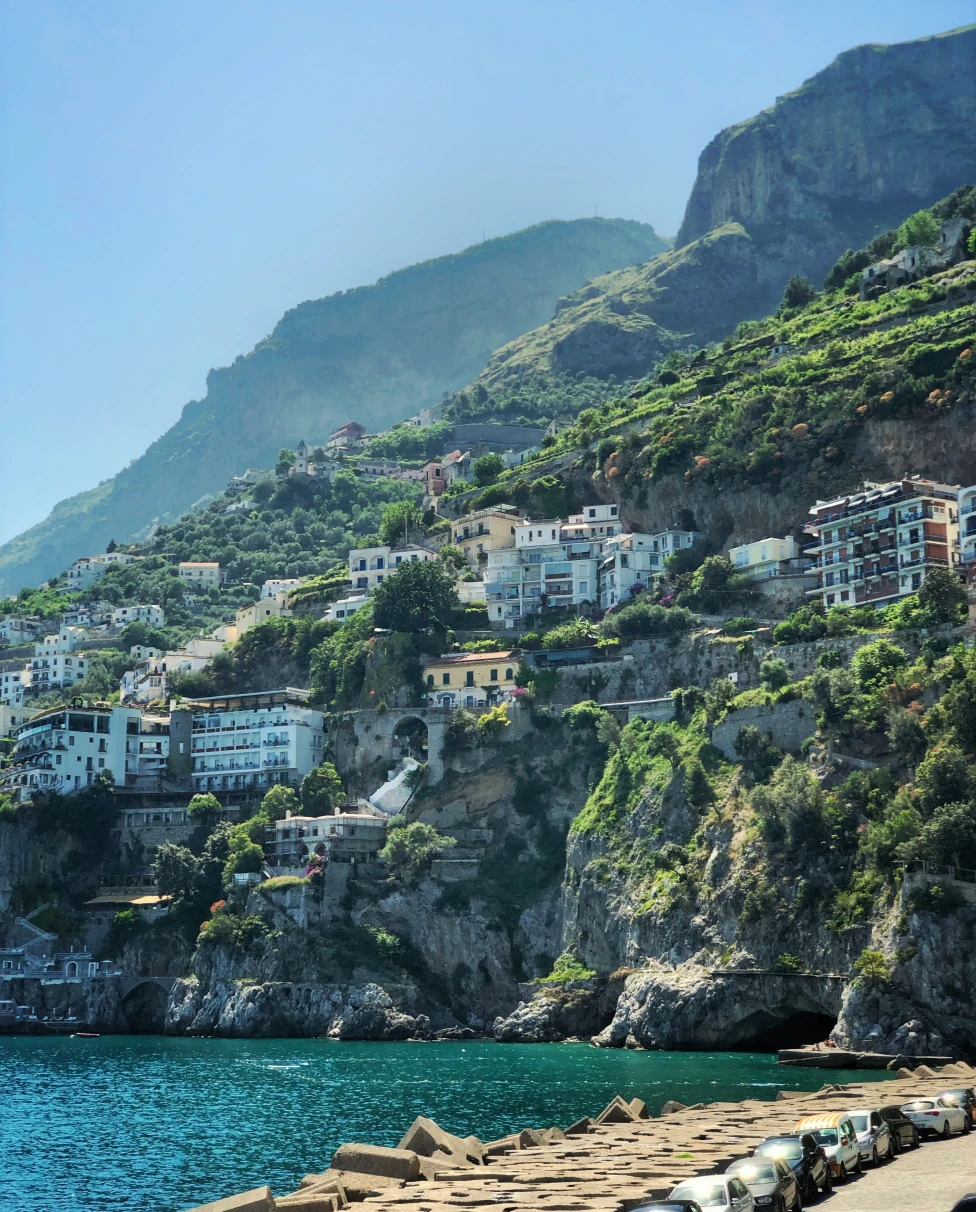 buildings on the side of a cliff near water during daytime