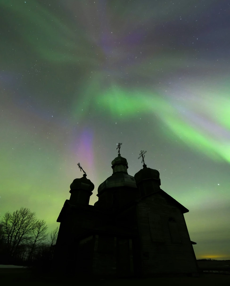 Aurora lights up the night sky over an abandoned church.