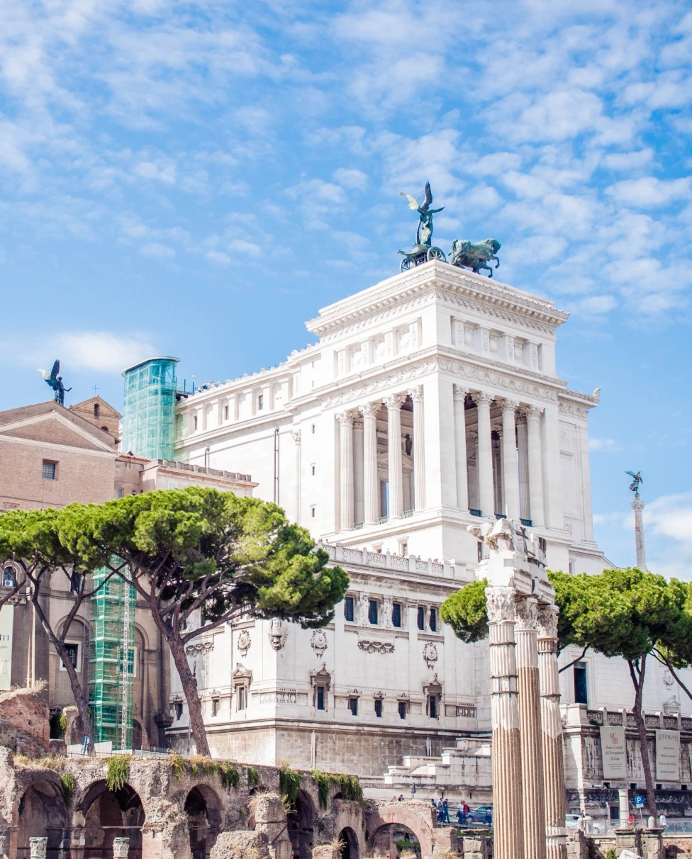 A view of historic buildings reaching toward the sky on a clear day dotted with clouds.