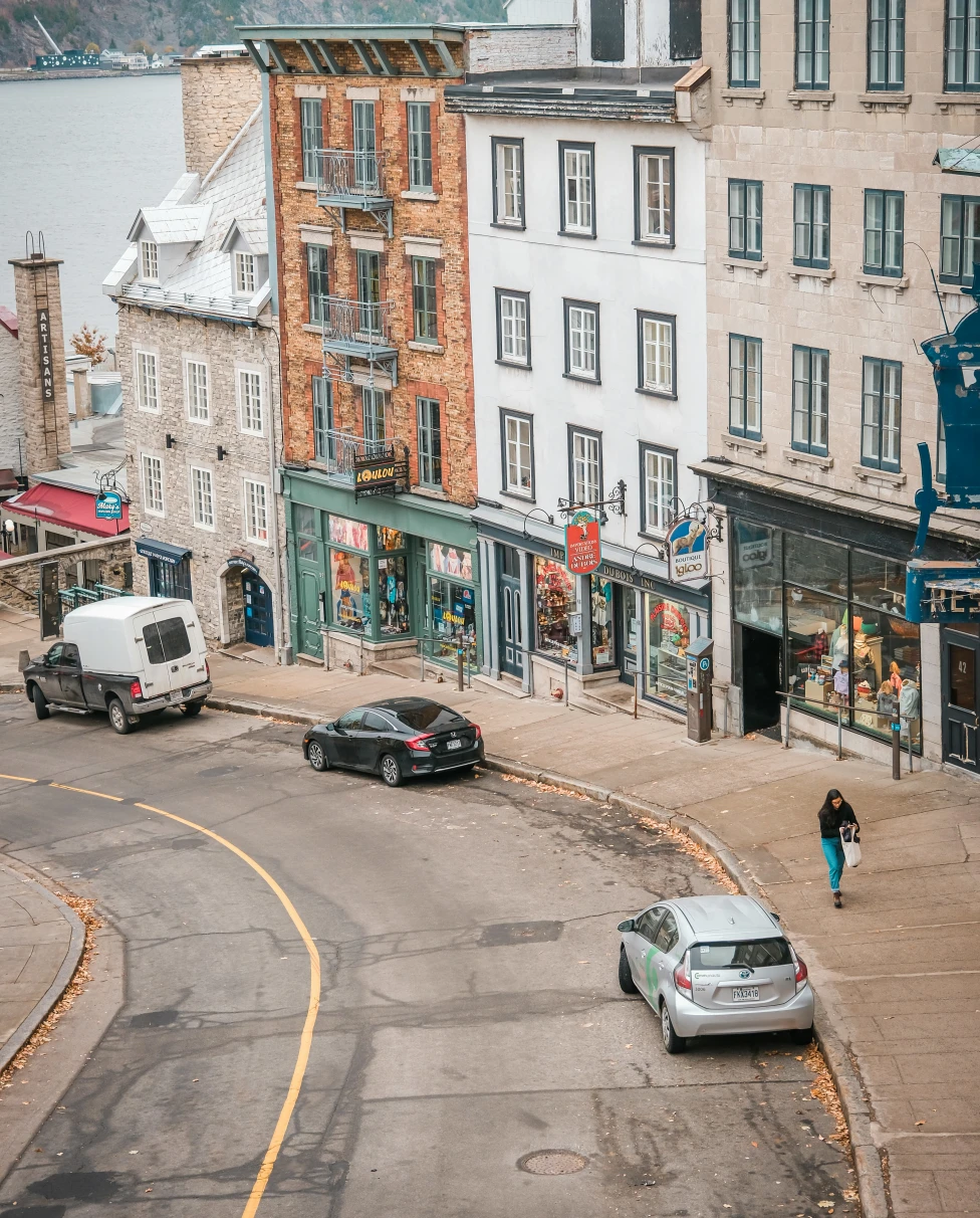 A view of a downward sloped street in Old Quebec with quaint buildings and stores.