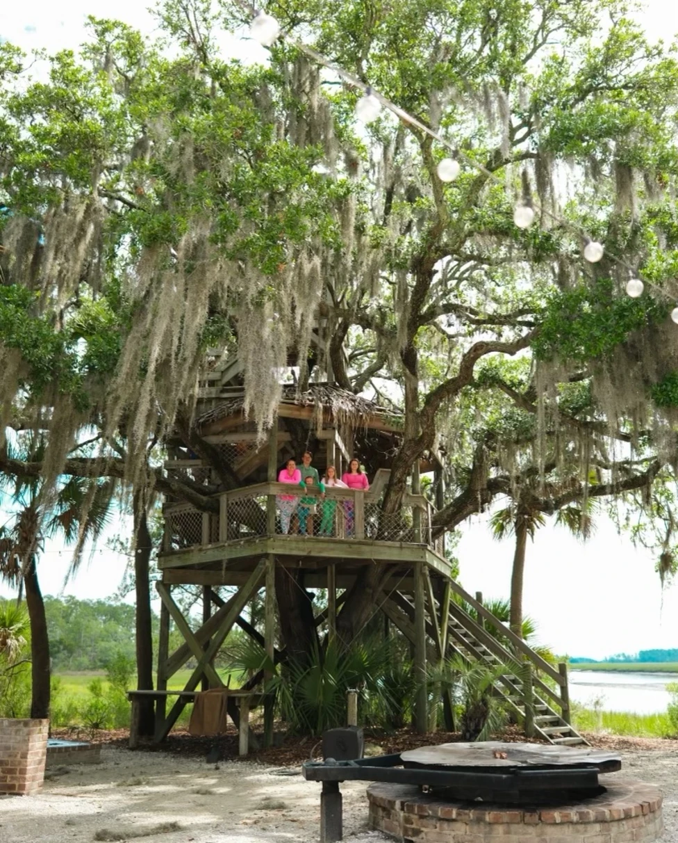 family stands in a treehouse in the forest in Palmetto.