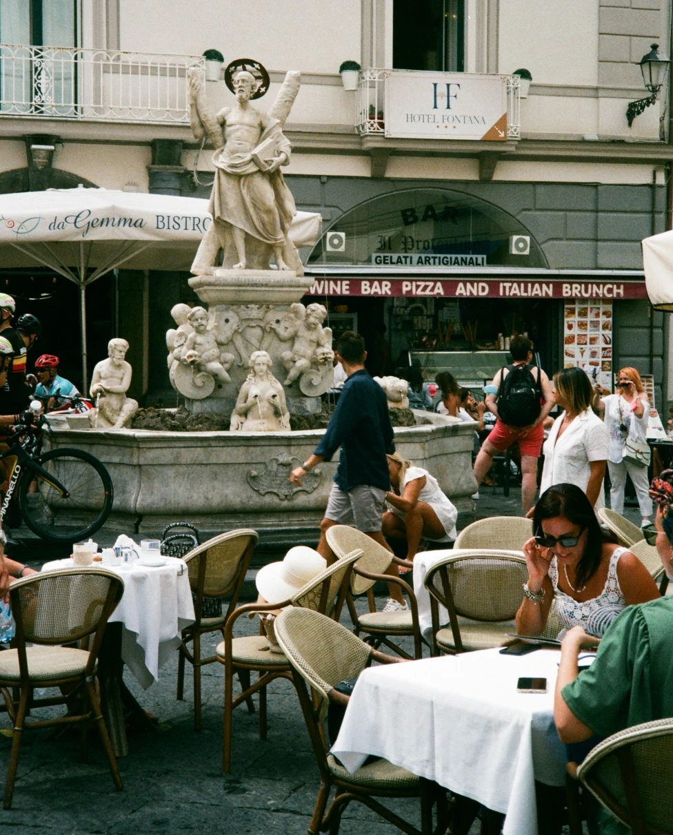 A group of people sitting on table in front of a fountain