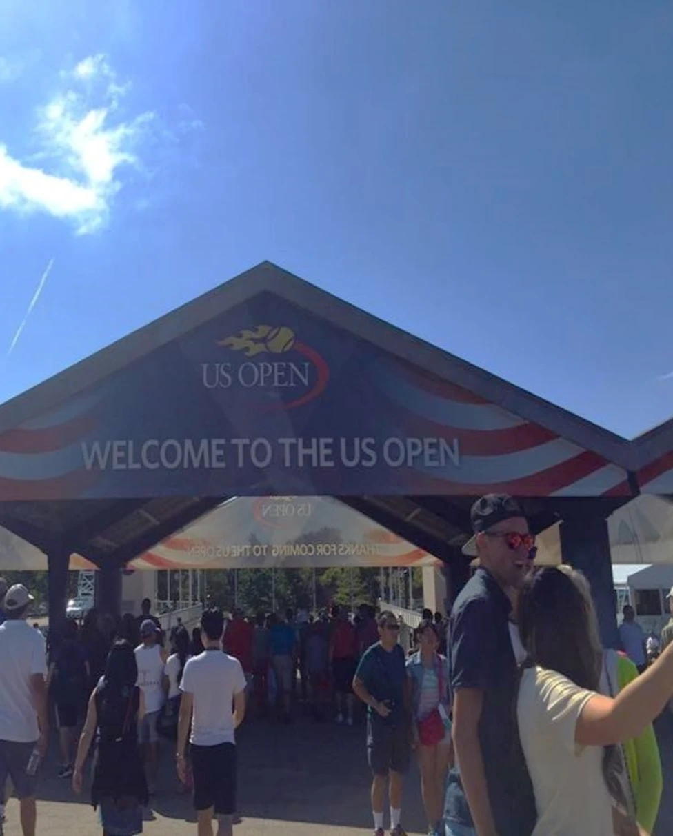 The image captures the excitement of people entering the US Open, highlighted by a prominent welcome sign.